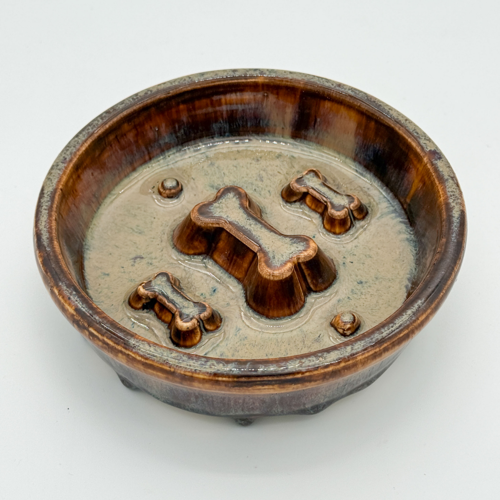 Medium Cappuccino-glazed handmade ceramic slow feeder dog bowl with raised bone-shaped obstacles inside to help encourage slower eating.