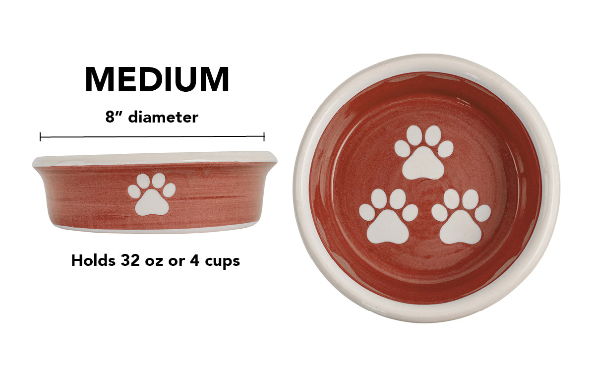 Medium terracotta handmade ceramic dog bowl with white paw prints, 8-inch diameter and 4-cup (32-ounce) capacity.