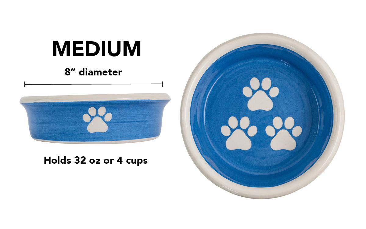 Medium blue handmade ceramic dog bowl with white paw prints, 8-inch diameter and 4-cup (32-ounce) capacity.