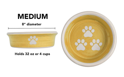 Medium yellow handmade ceramic dog bowl with white paw prints, 8-inch diameter and 4-cup (32-ounce) capacity.